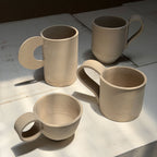 Four ceramic slab template mugs on a light surface with a dark background
