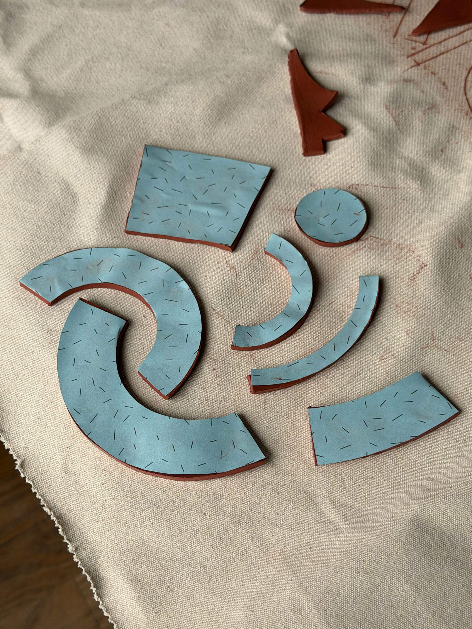 Ceramic slab template pieces on a textured canvas
