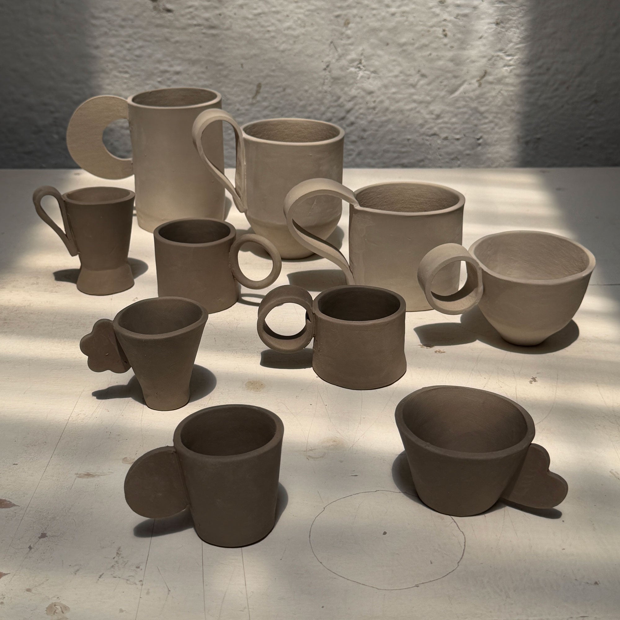 Collection of slab templates mugs on a light surface with a textured wall background